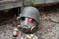 Vintage-style gas mask with red lenses on a gravel surface