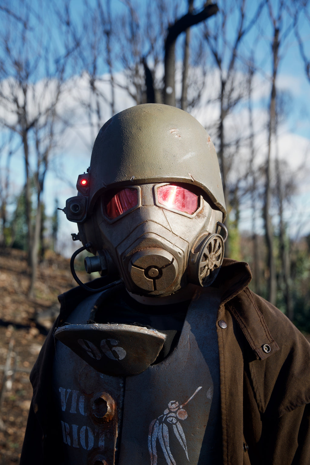 Person wearing a detailed gas mask with red lenses outdoors