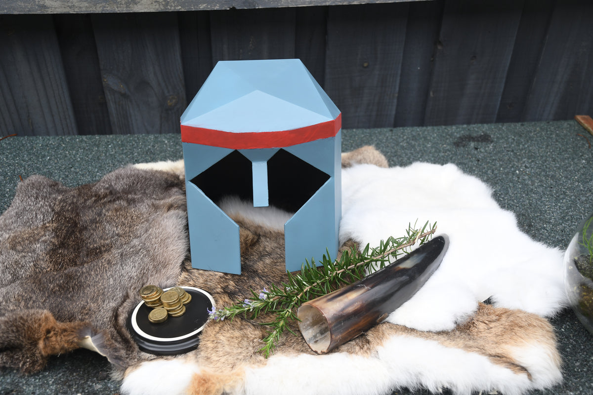Small blue and red building-like structure on a textured surface with natural elements.