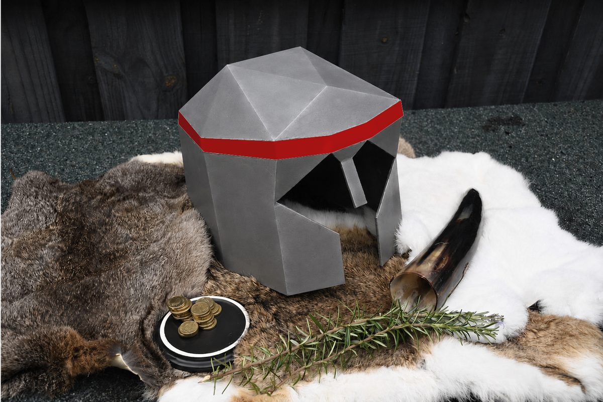 A gray medieval-style helmet with a red band sits on a fur rug with a horn, coins, and rosemary in front of a dark wood background.